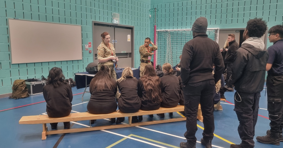 Students sat on a bench listening to a talk from the Royal Logistics Core